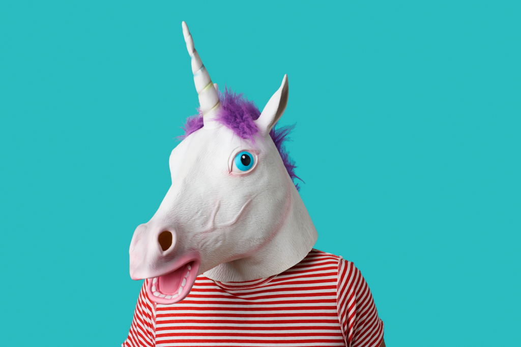 A person wearing a unicorn mask with a teal background