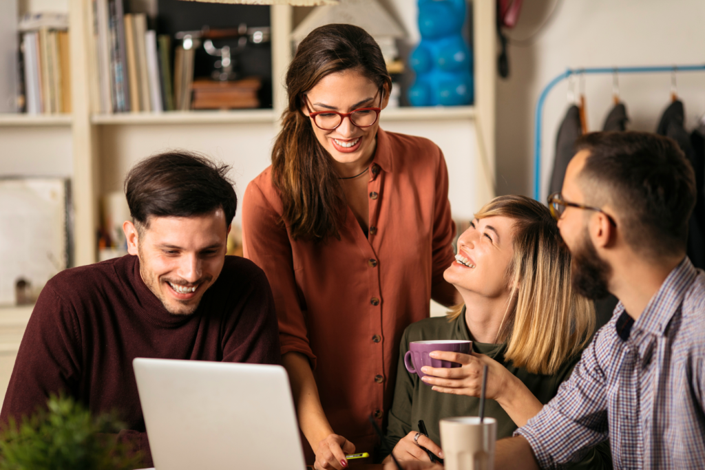 Team members working around a laptop and smiling.